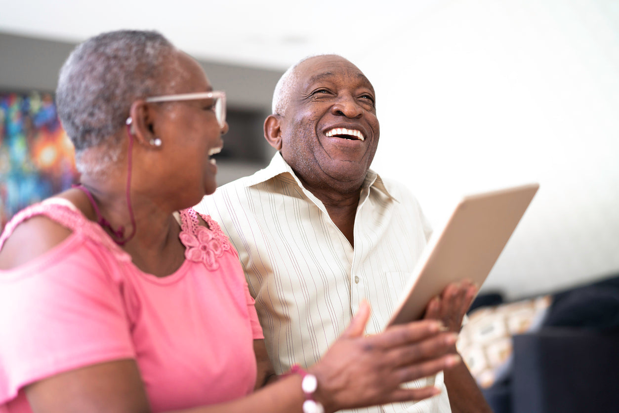 african american couple laughing, looking at a tablet