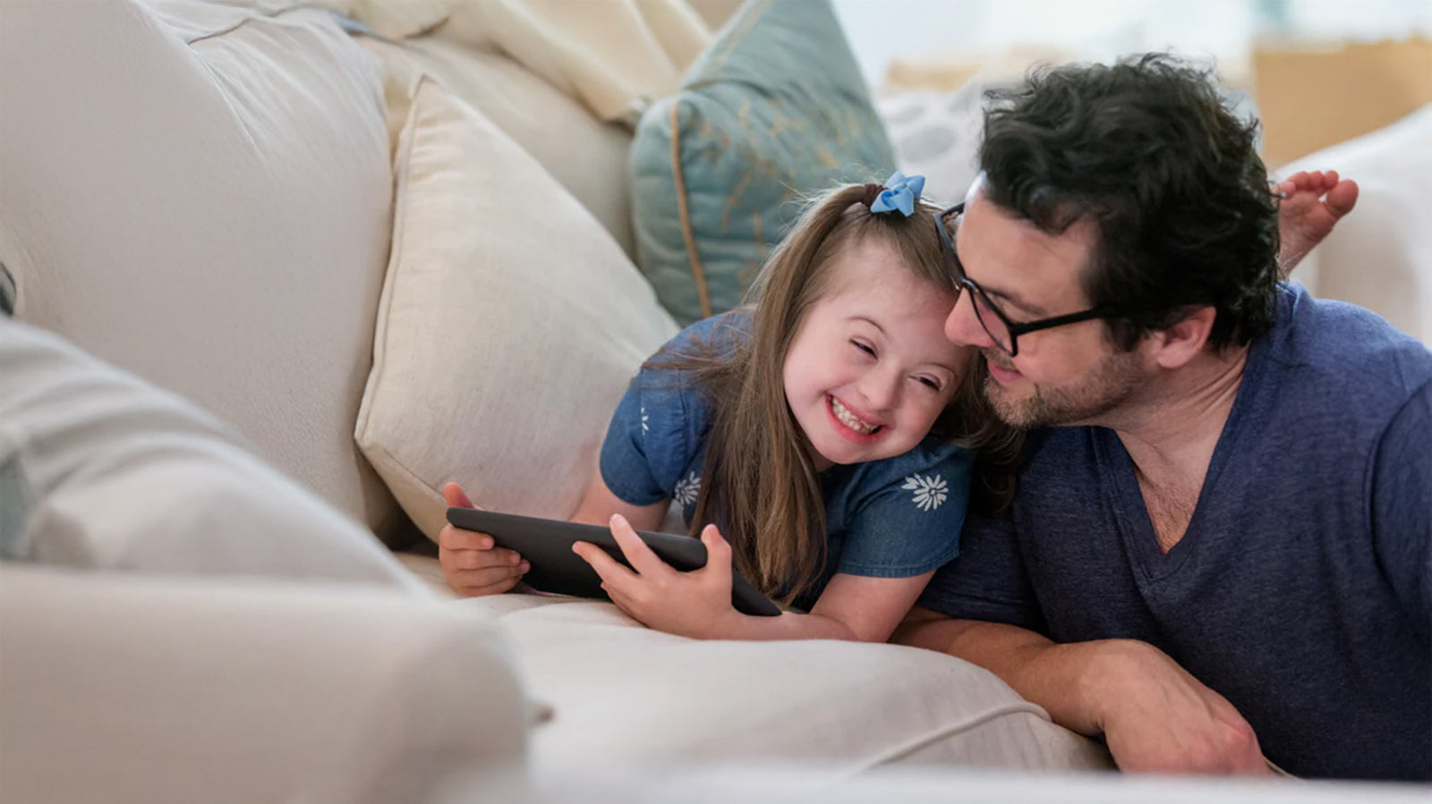 Father and daughter on the couch with a tablet